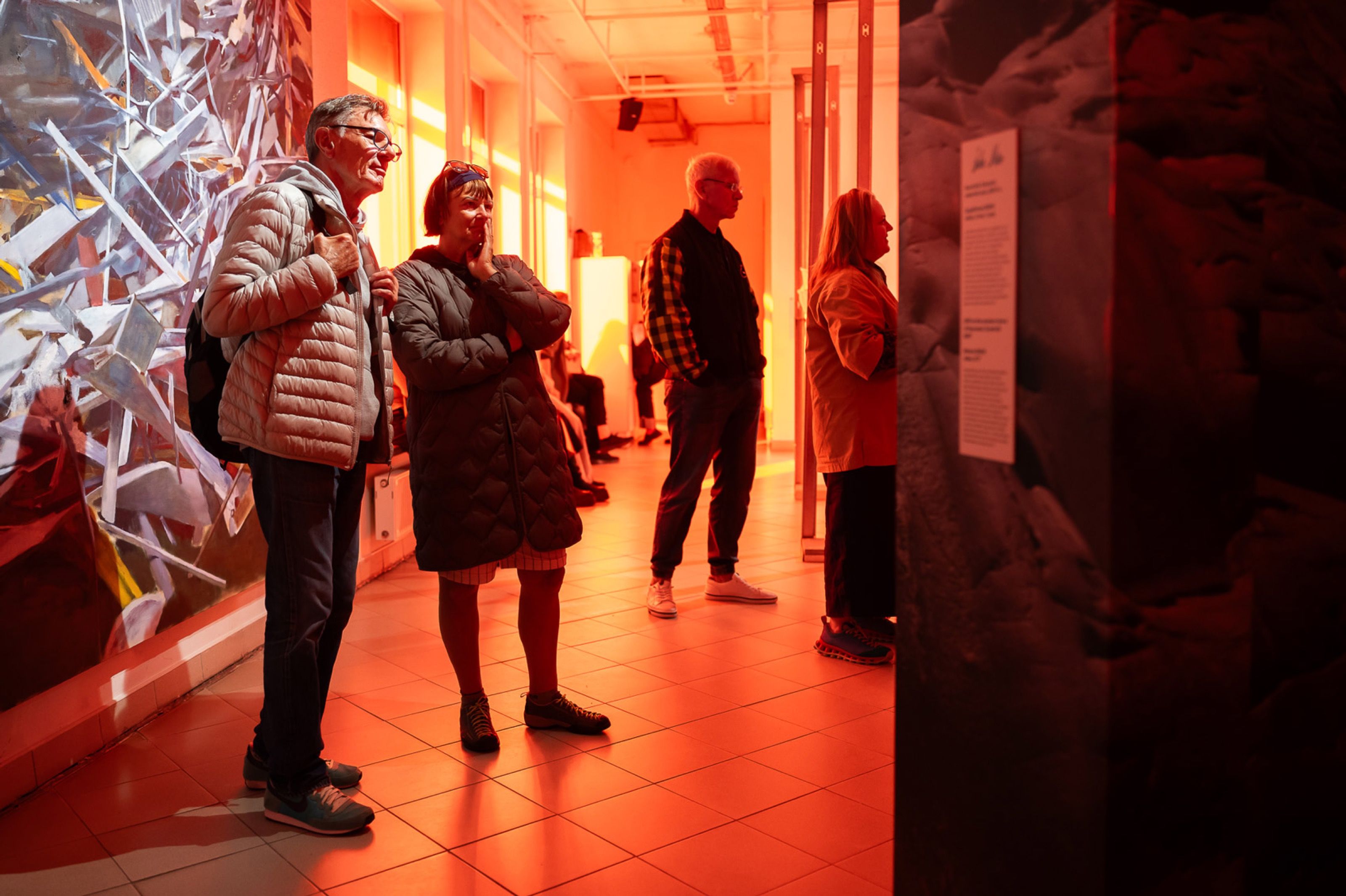 Visitors in a red-lit gallery at the Noise Portals exhibition