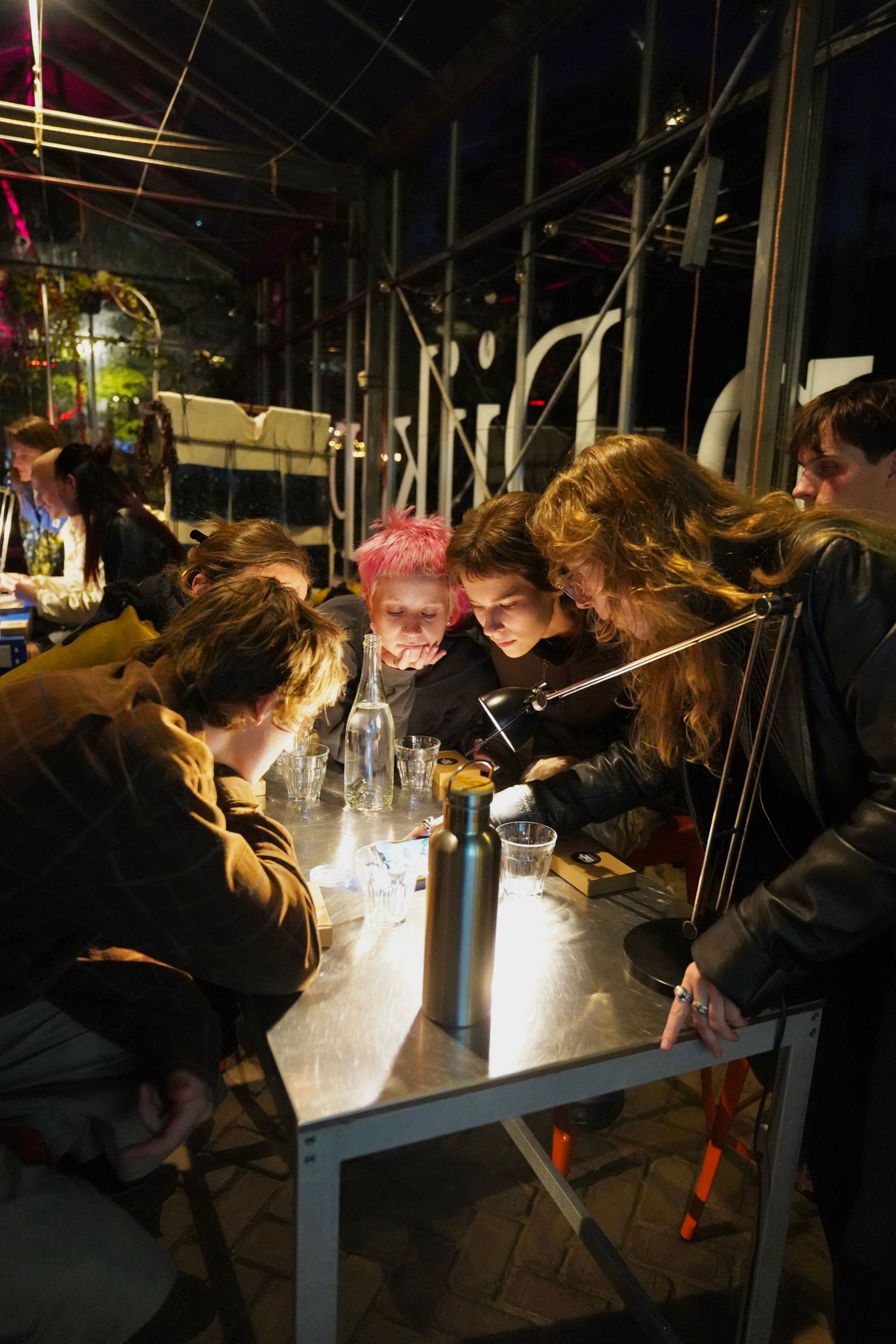 Participants leaning over a lit table during an evening slime mould workshop