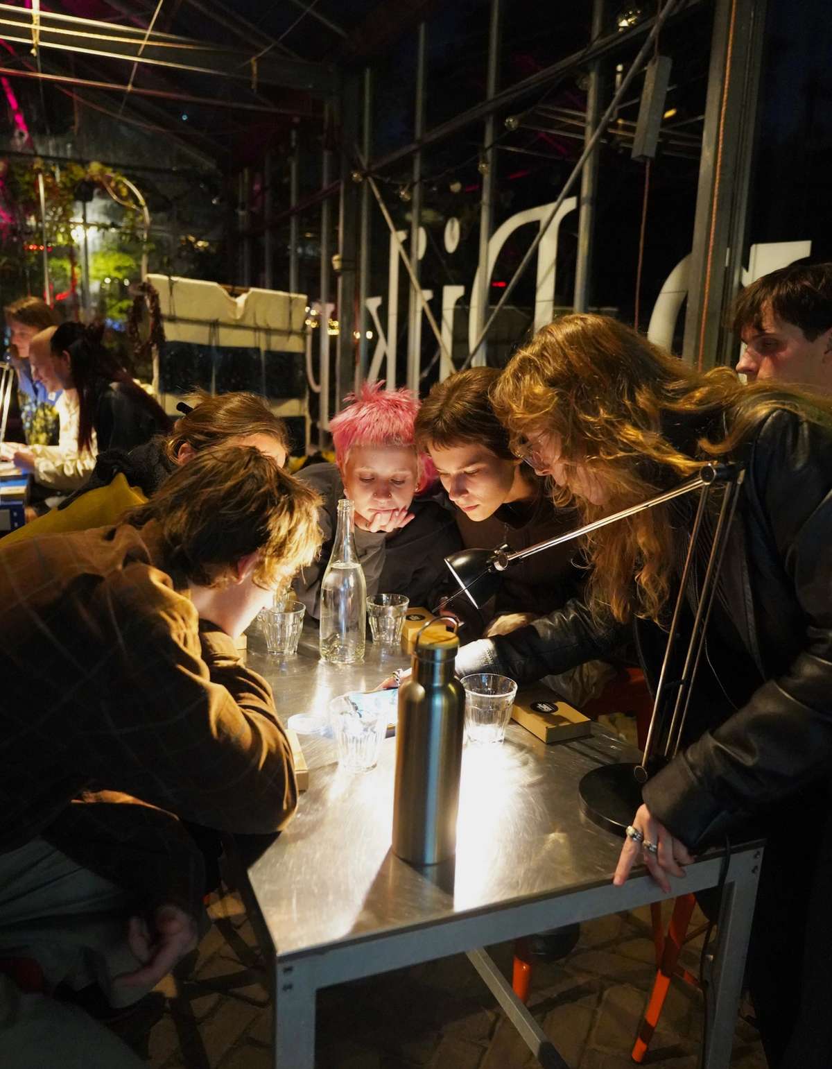 Participants leaning over a lit table during an evening slime mould workshop