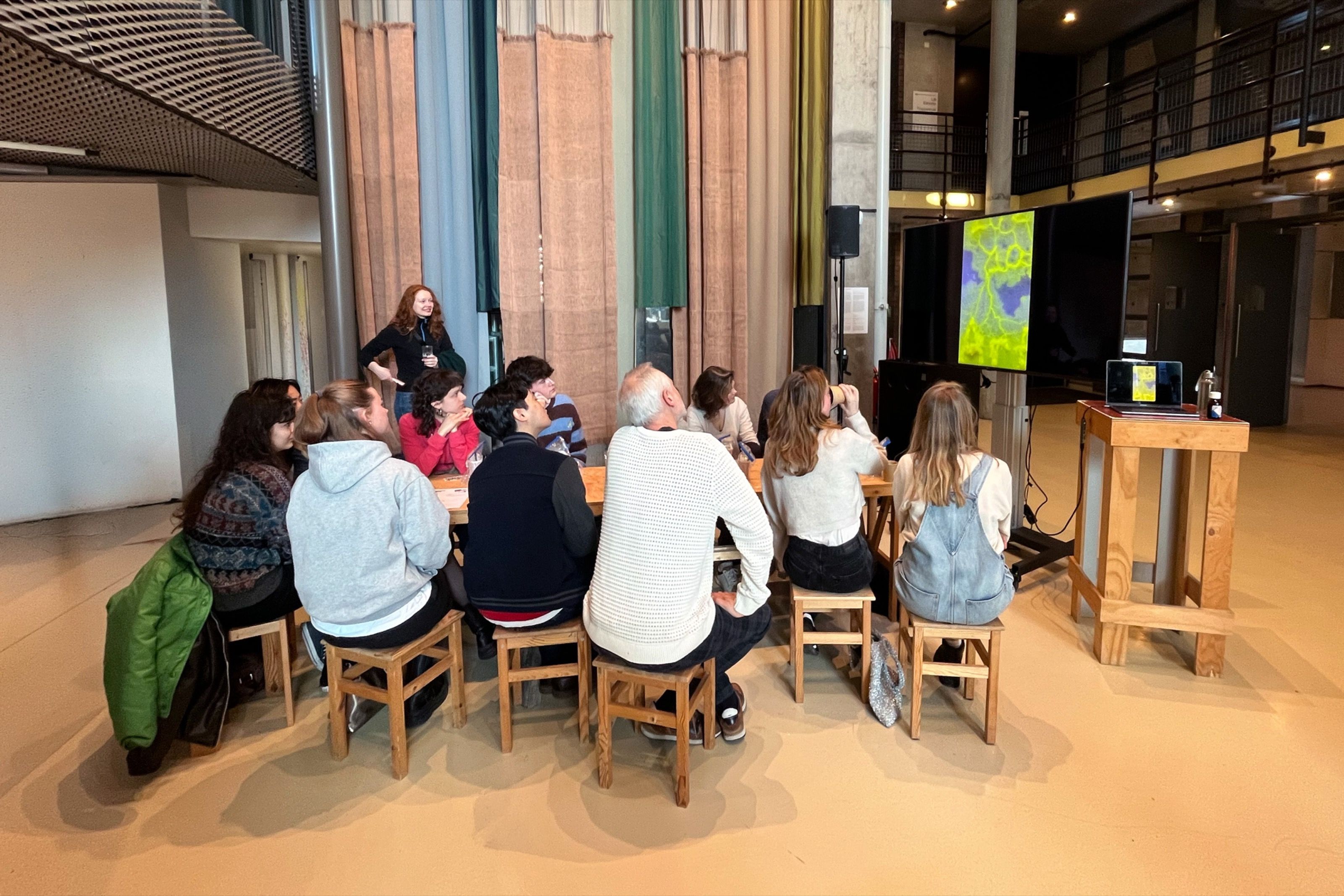 Participants seated in a circle during a slime mould workshop in an industrial hall