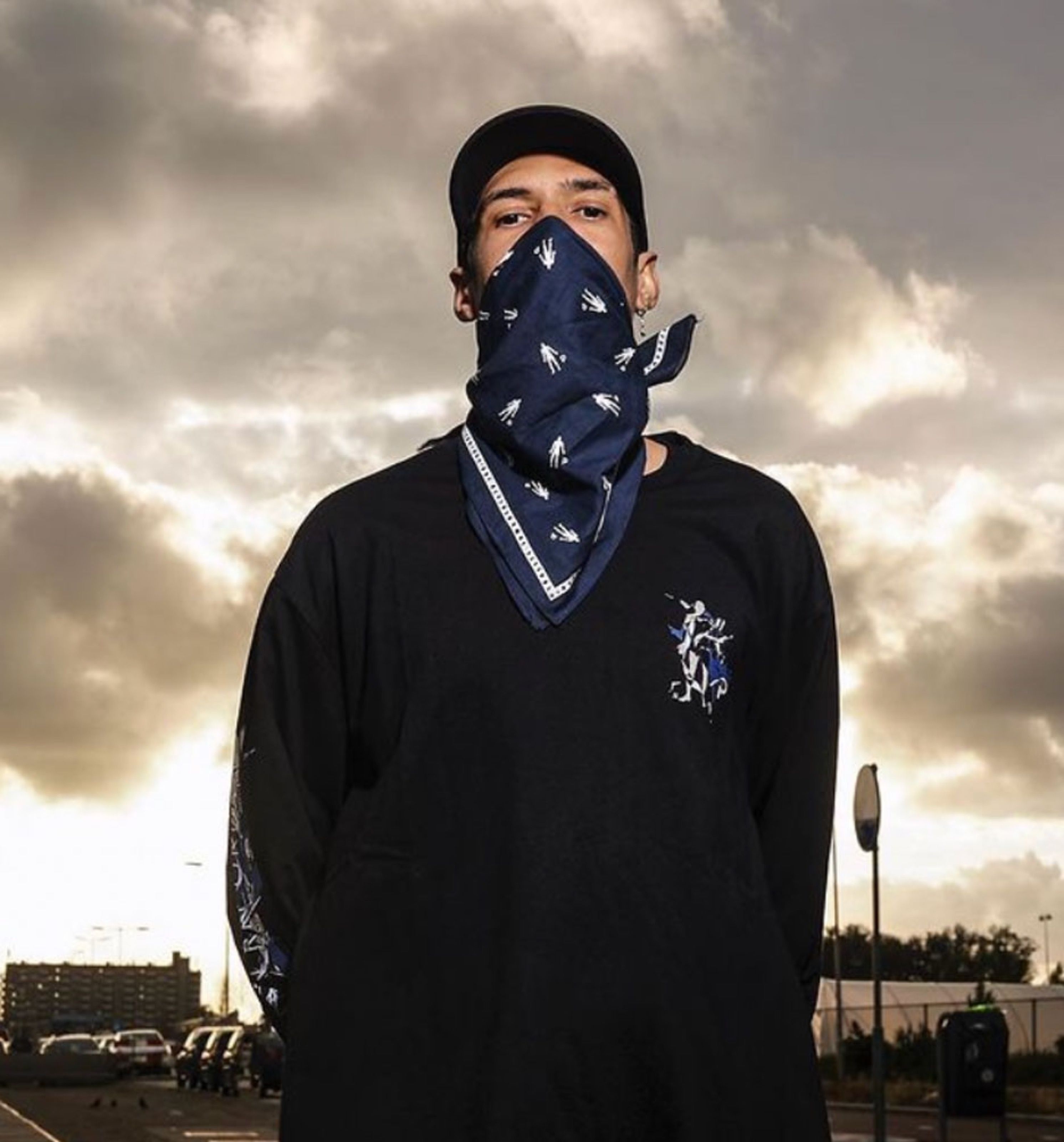Person wearing a navy bandana over the face and a black long-sleeve shirt