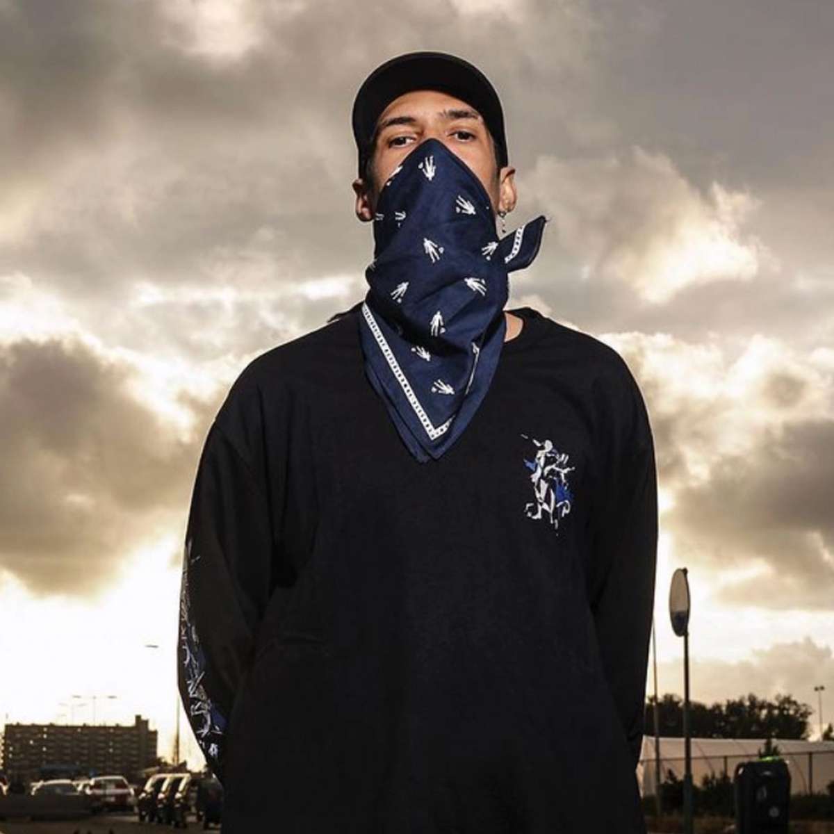 Person wearing a navy bandana over the face and a black long-sleeve shirt