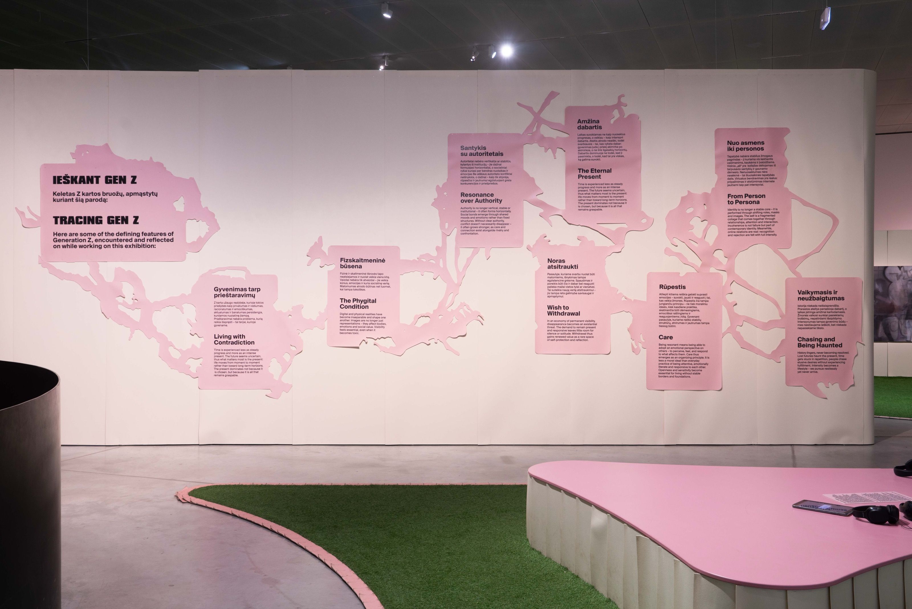 Long exhibition wall with pink organic-shaped text panels, Gen Z. All at Once