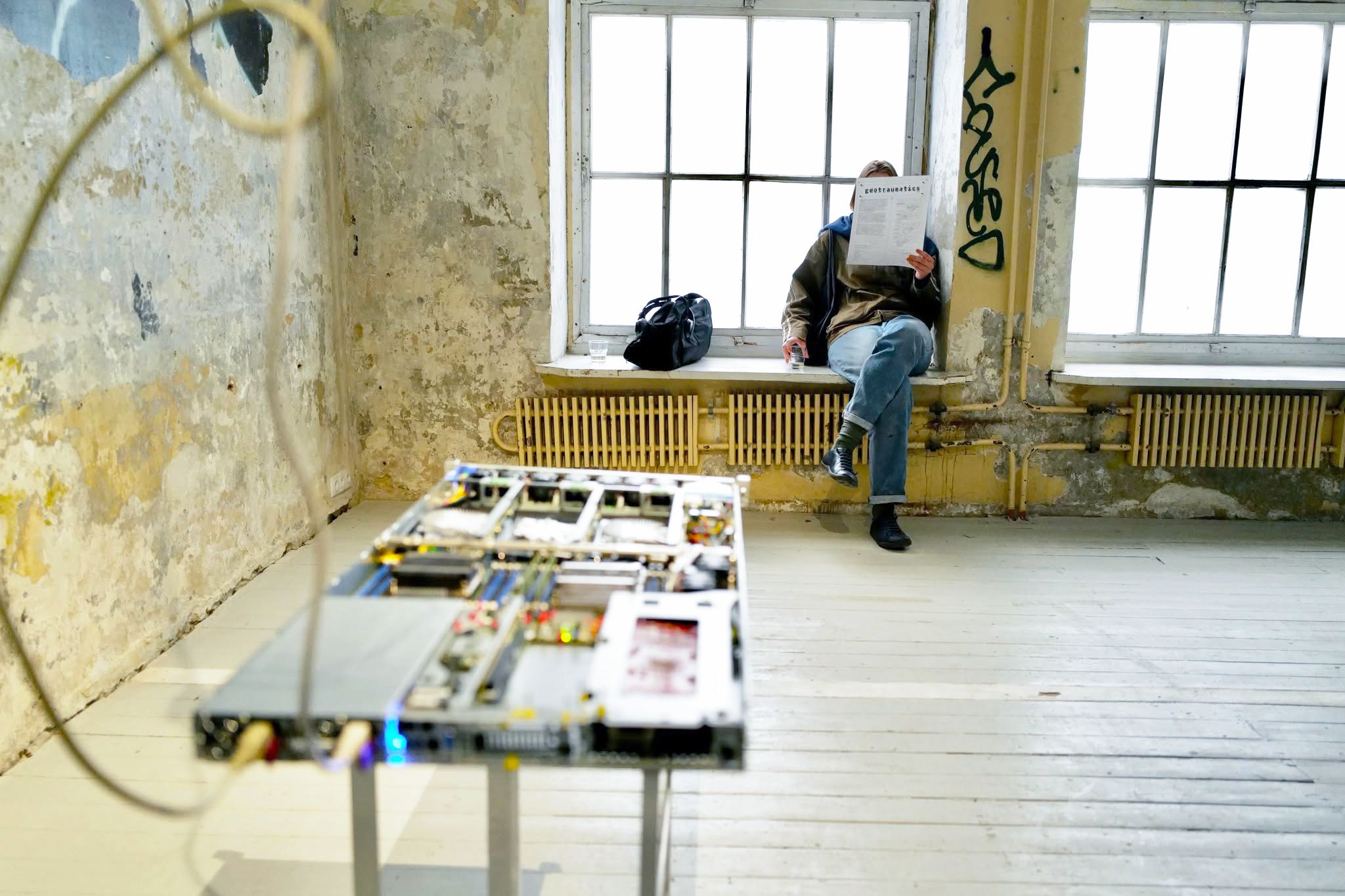 Exhibition room at Atletika gallery with a visitor reading by the window