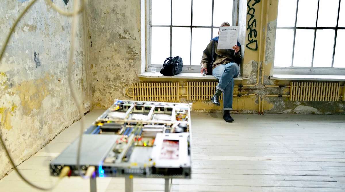 Exhibition room at Atletika gallery with a visitor reading by the window