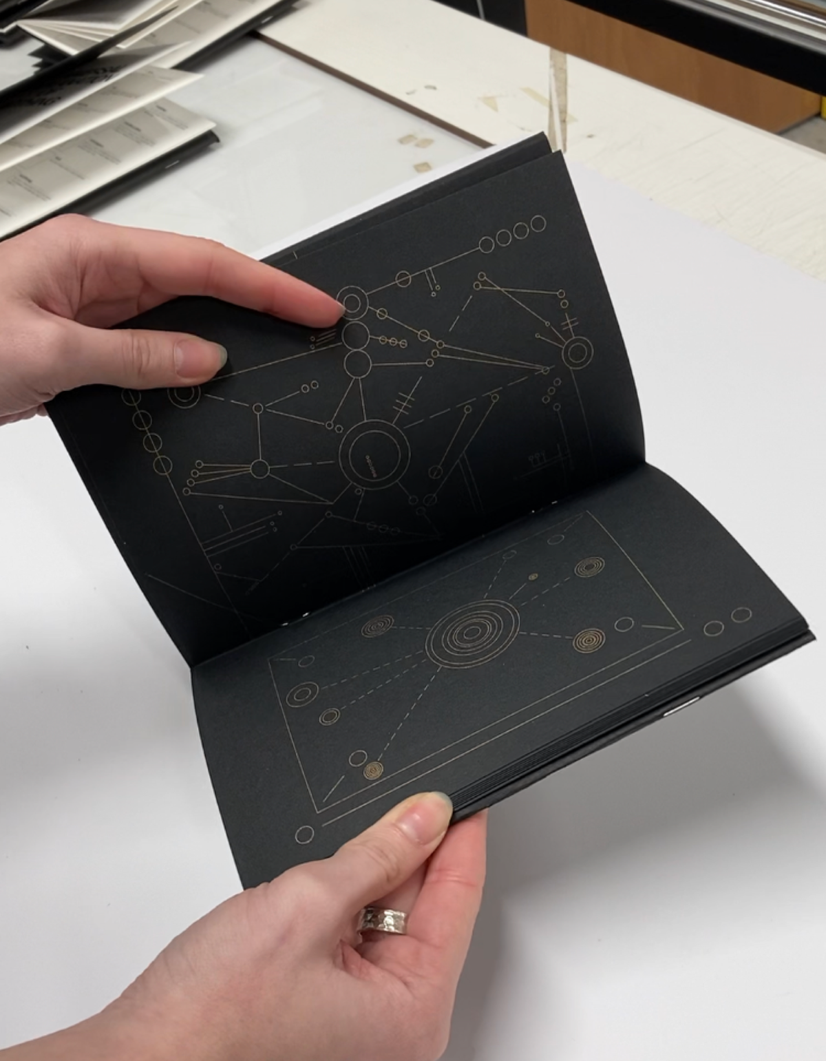 Open Universal Explanation of Nothing book with gold line drawings on black pages