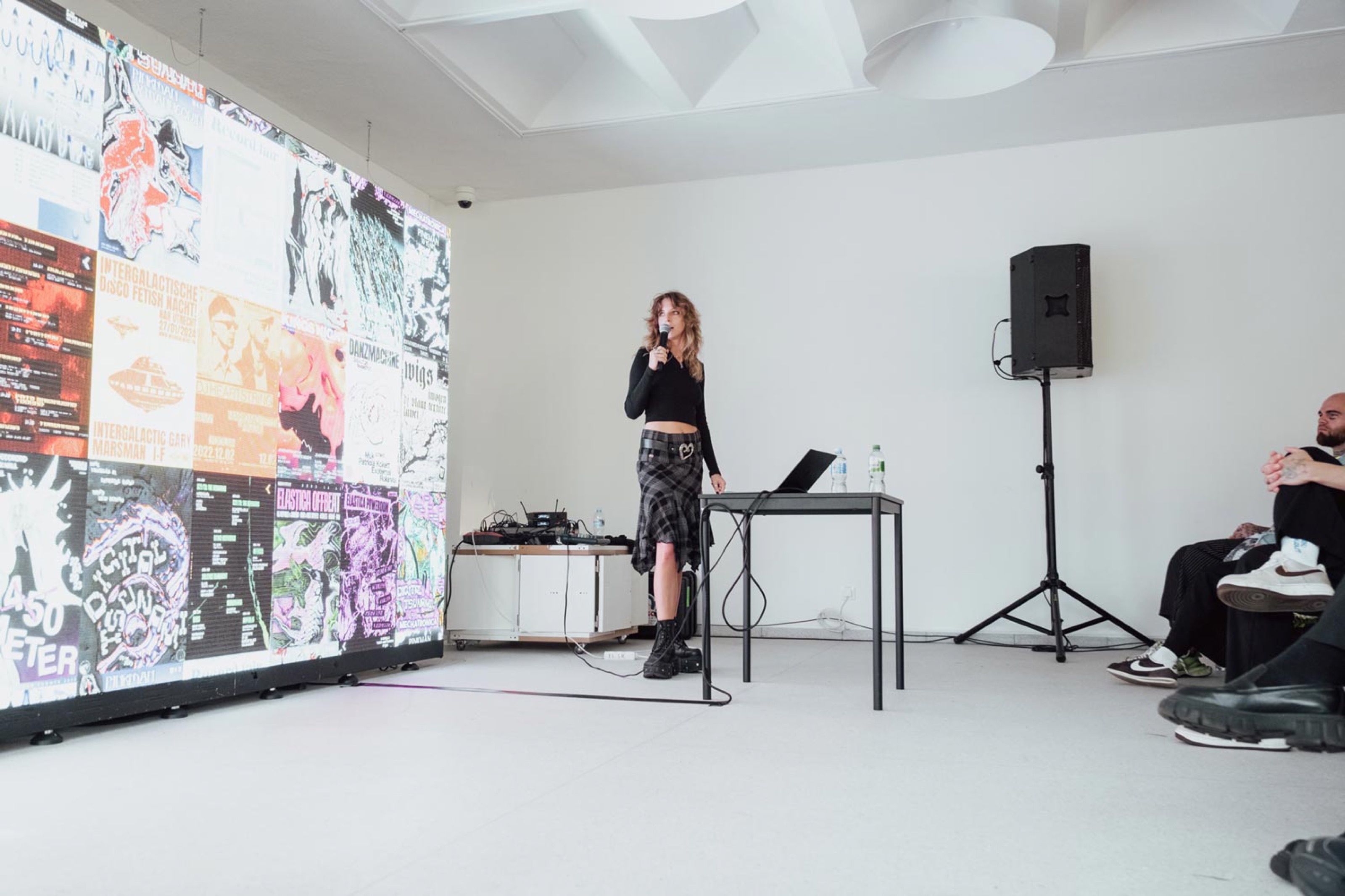 Speaker giving a talk in front of a wall-sized projection of posters