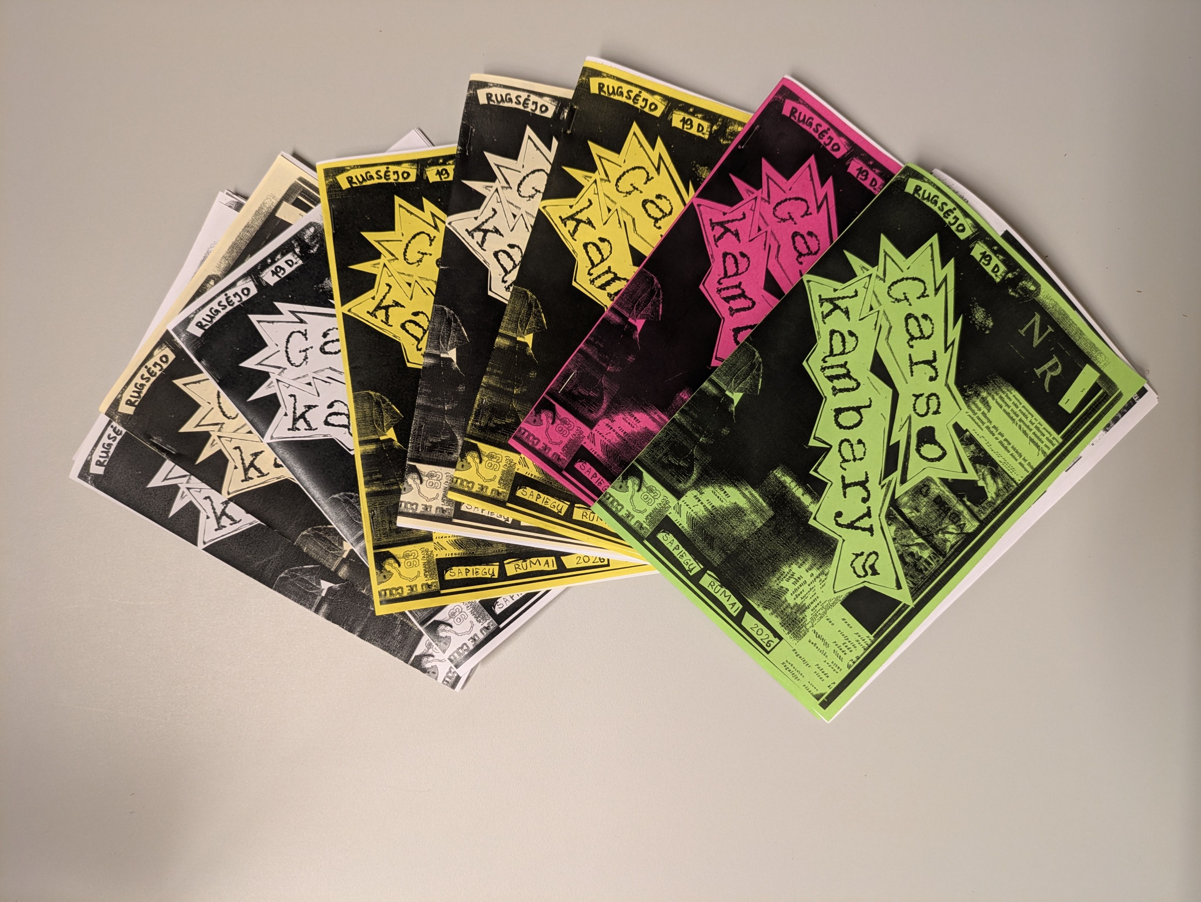A fan of finished zines printed in black, yellow, pink and green
