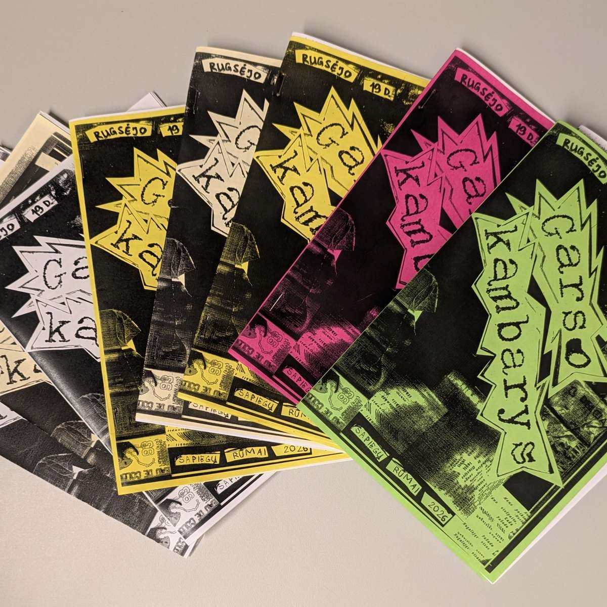 A fan of finished zines printed in black, yellow, pink and green