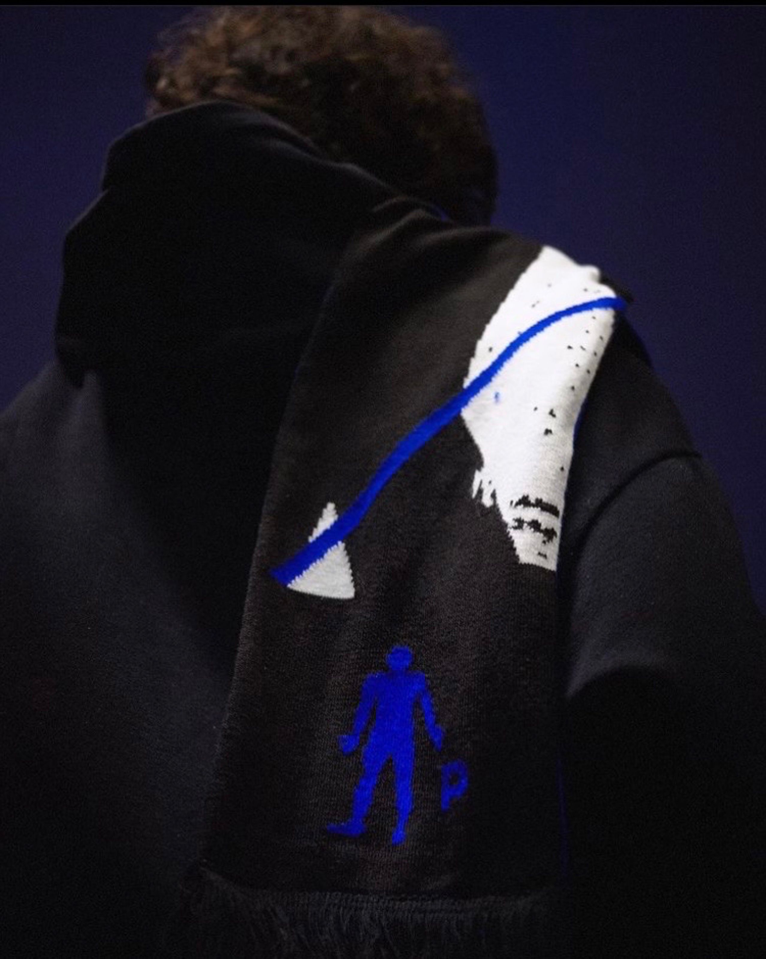 Back of a person wearing a black Pinkman scarf with blue figure logo