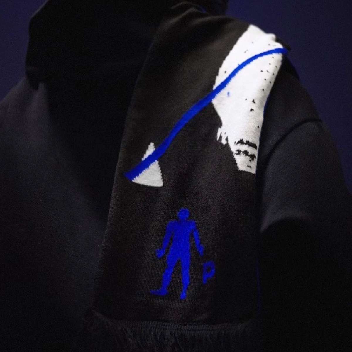 Back of a person wearing a black Pinkman scarf with blue figure logo