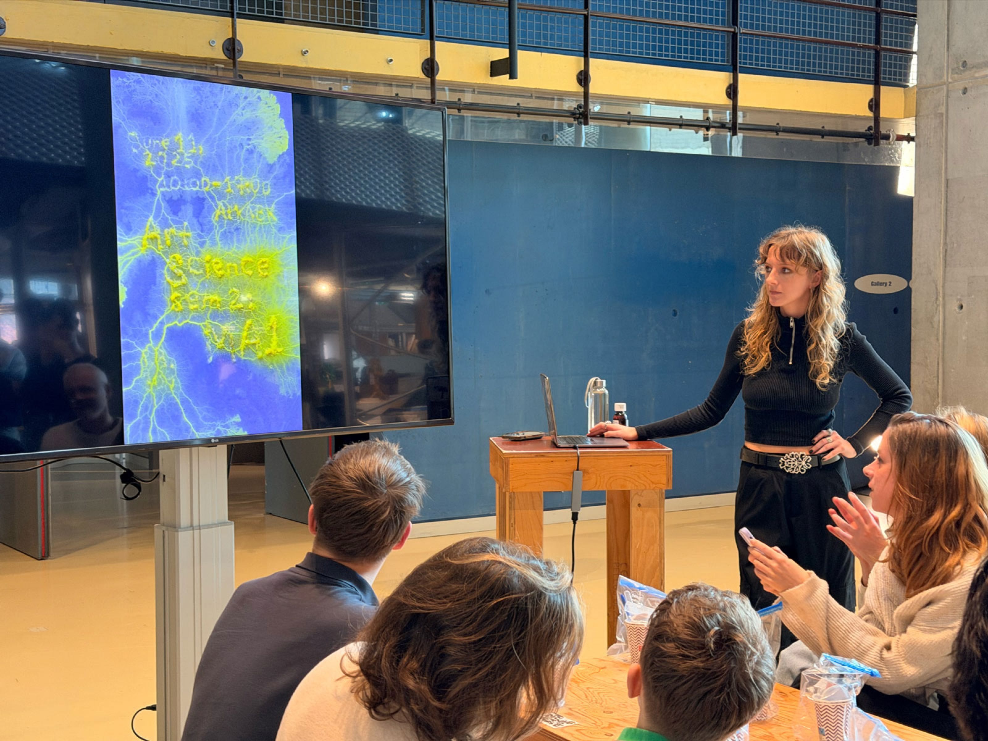 Workshop leader presenting slime mould images on a screen to seated participants