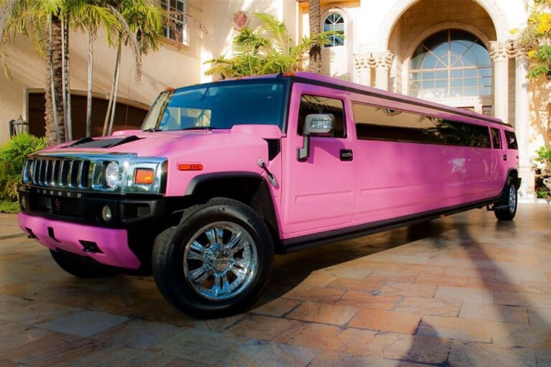 A pink Hummer stretch limousine lit at night