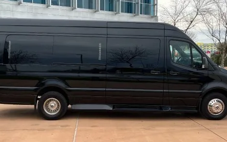 Black Mercedes Sprinter limousine van, side view, parked outside an office building