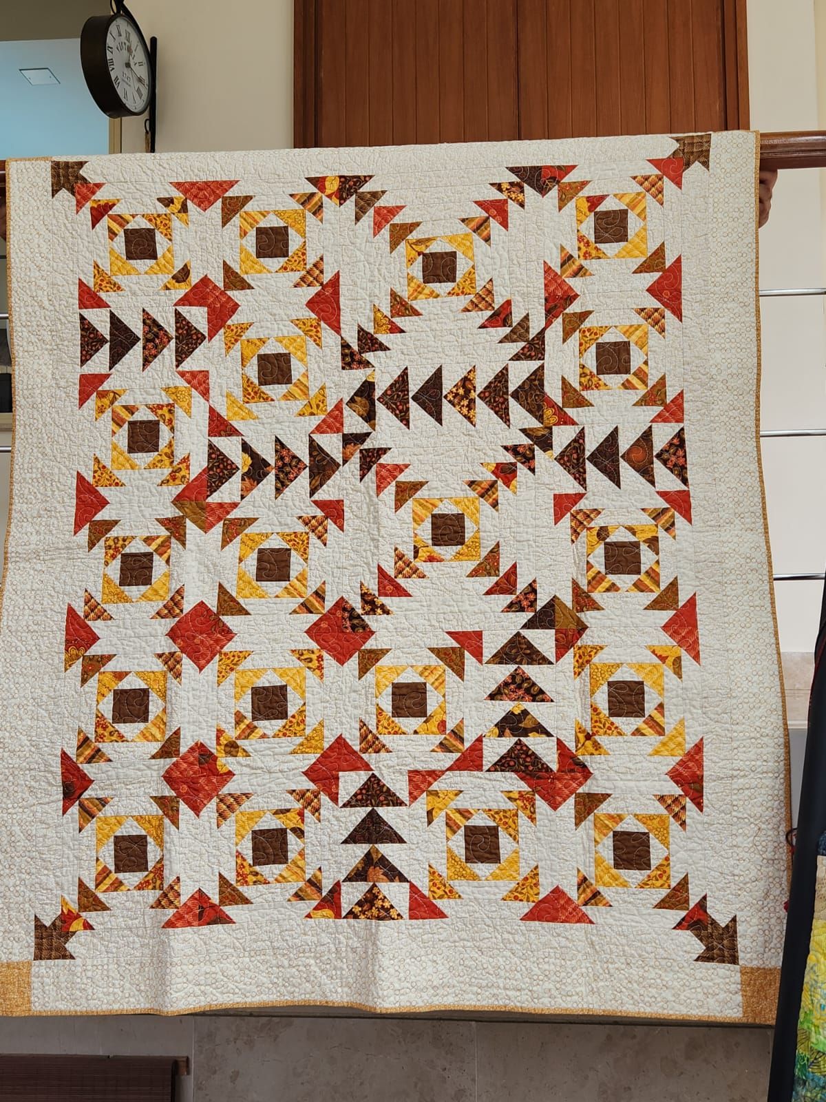 Autumn flying geese lap quilt hung flat, showing the full rust and gold pattern