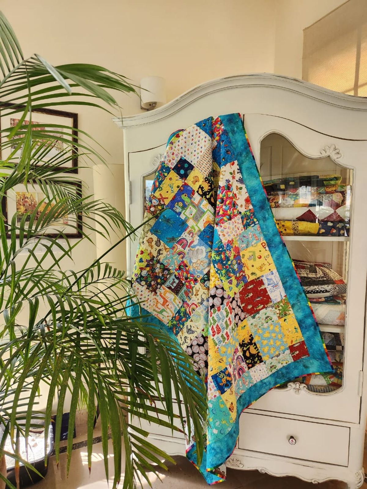 Child's I Spy quilt draped over a painted armoire