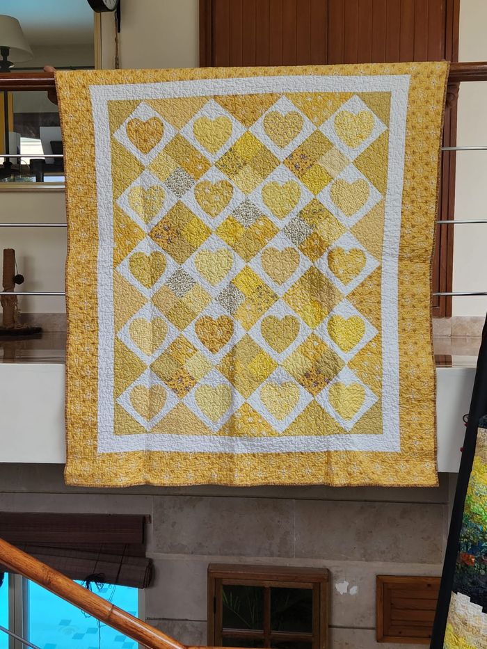 Golden hearts quilt hung flat, showing the full trellis of gold heart blocks