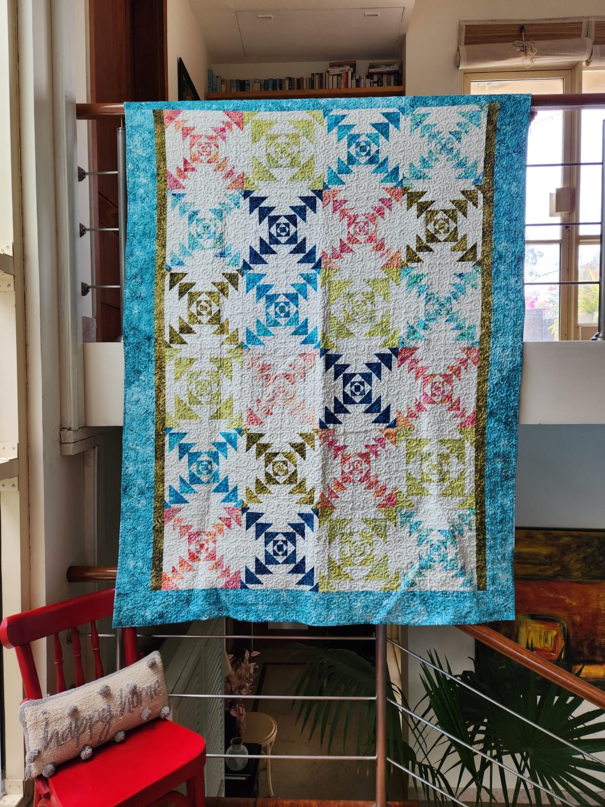 Teal flying geese throw hung flat, showing the full teal, coral and mustard pattern