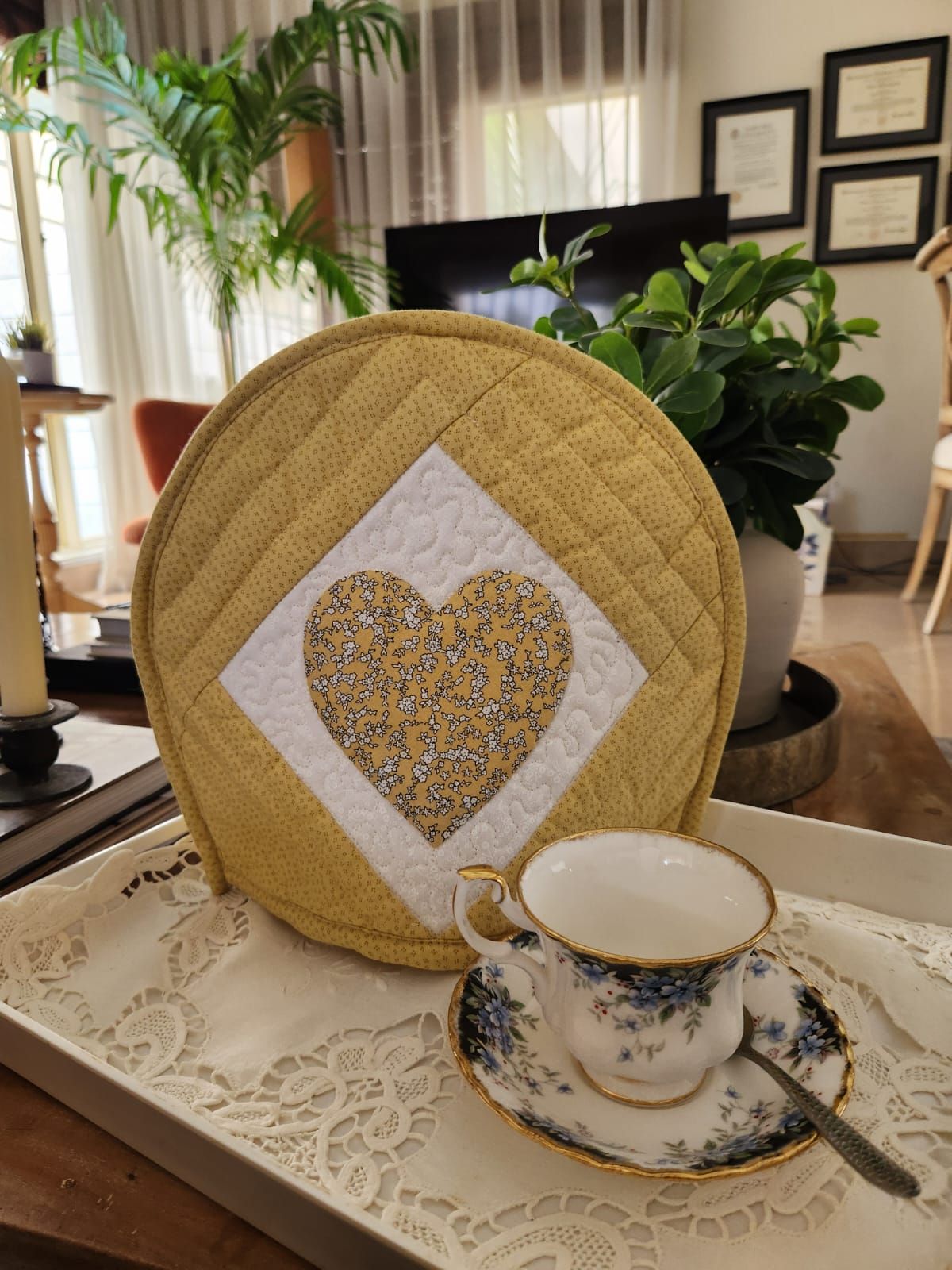 Mustard-gold quilted tea cosy with a floral appliqué heart on a white diamond