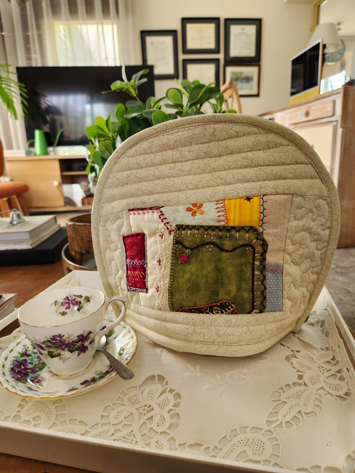 Cream tea cosy with a crazy-patchwork block of green velvet and hand embroidery