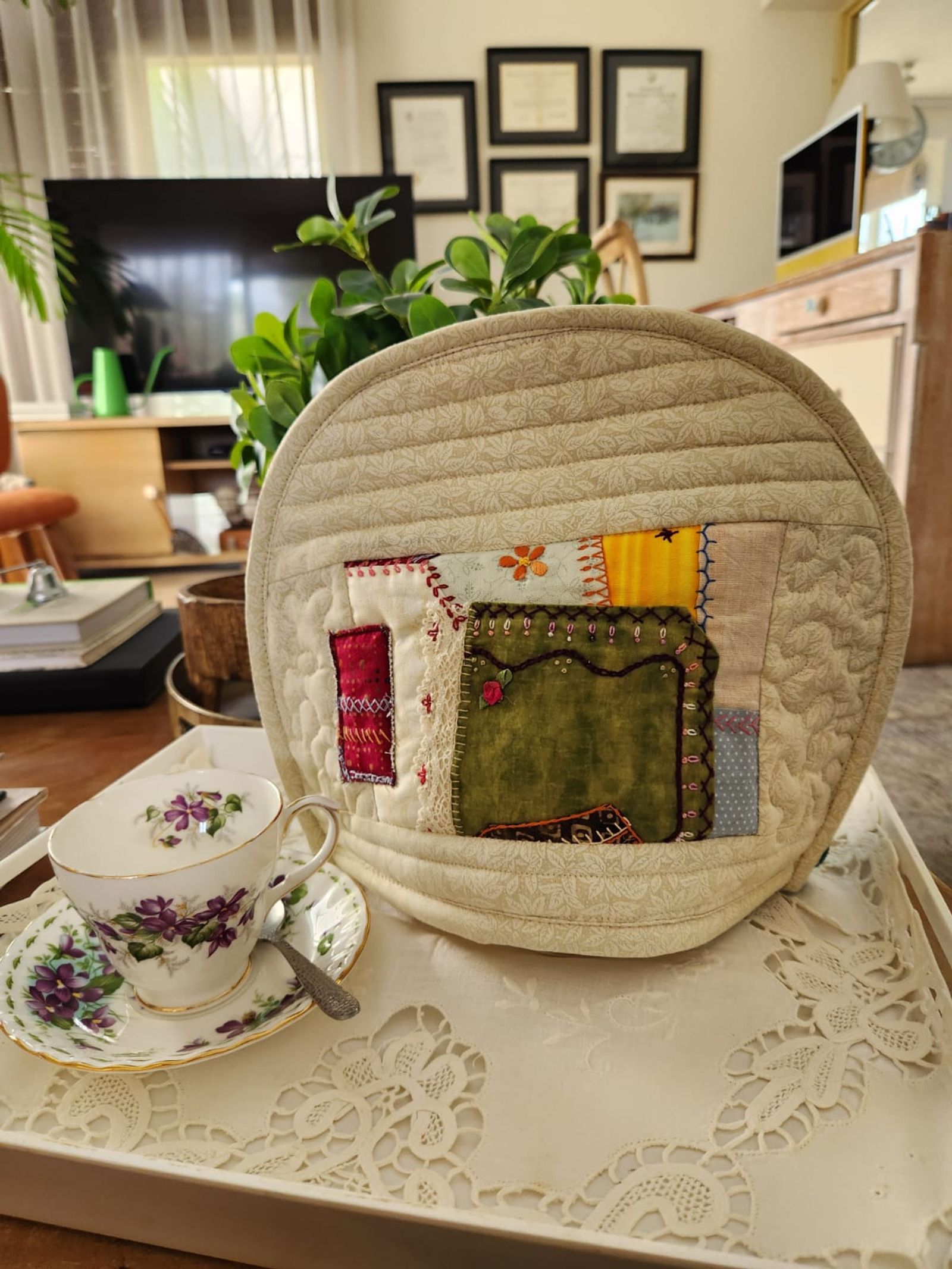 Cream tea cosy with a crazy-patchwork block of green velvet and hand embroidery