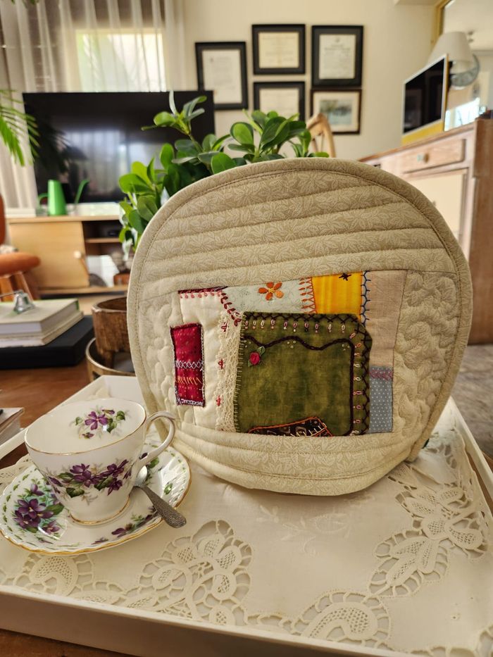 Cream tea cosy with a crazy-patchwork block of green velvet and hand embroidery