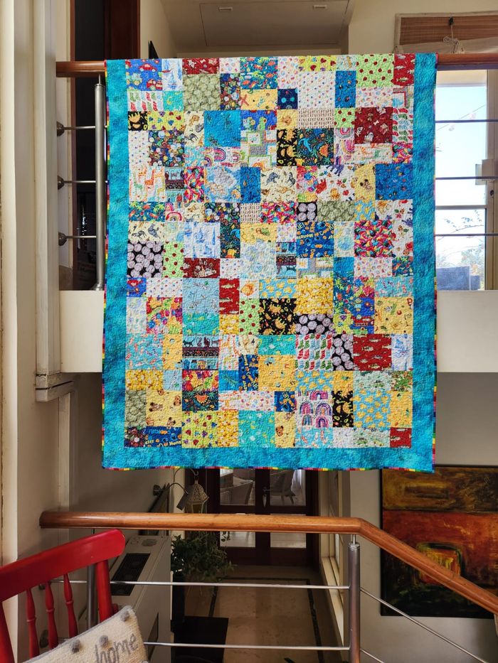 Child's I Spy quilt hung flat, showing the full patchwork of novelty prints