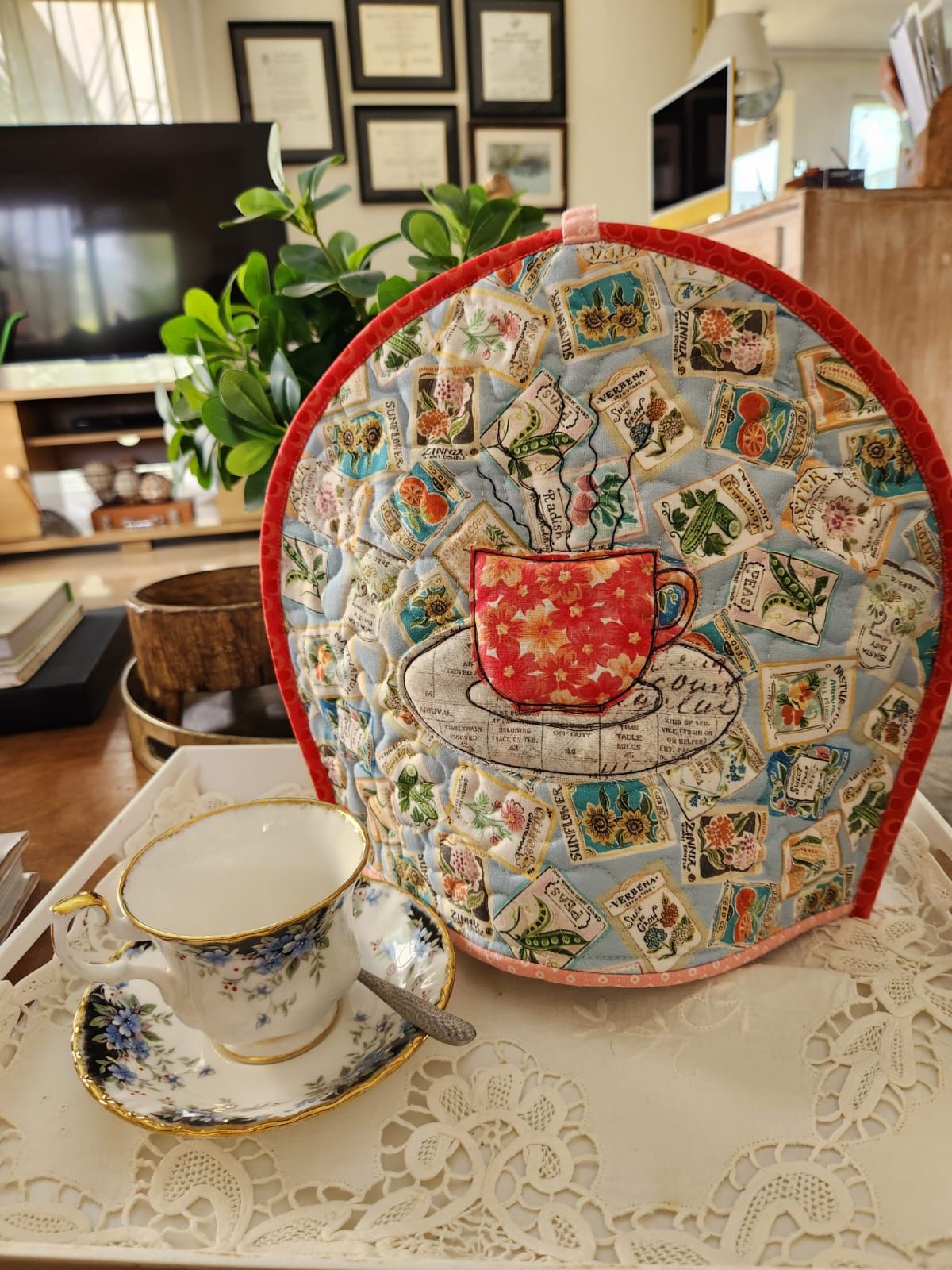 Front of a double-sided tea cosy: an appliqué floral teacup on seed-packet fabric