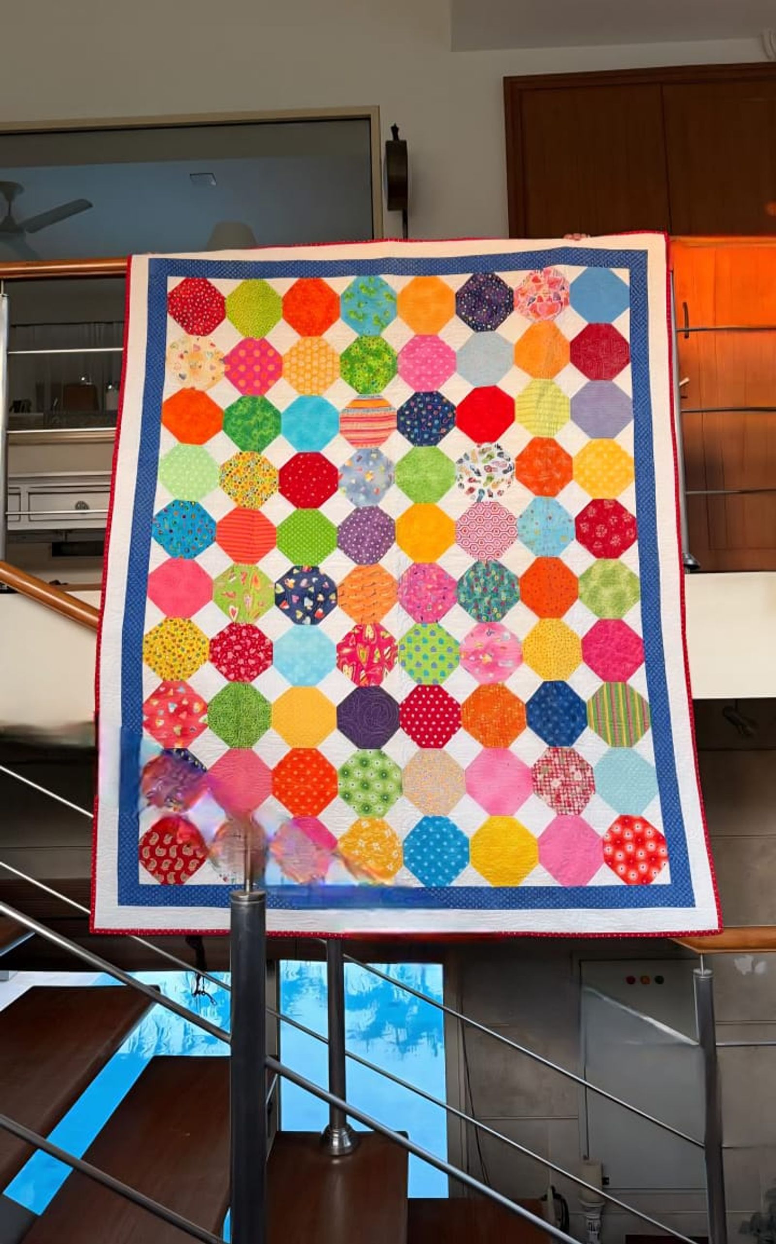 Rainbow dots quilt hung flat, showing the full pattern of scrappy coloured dots