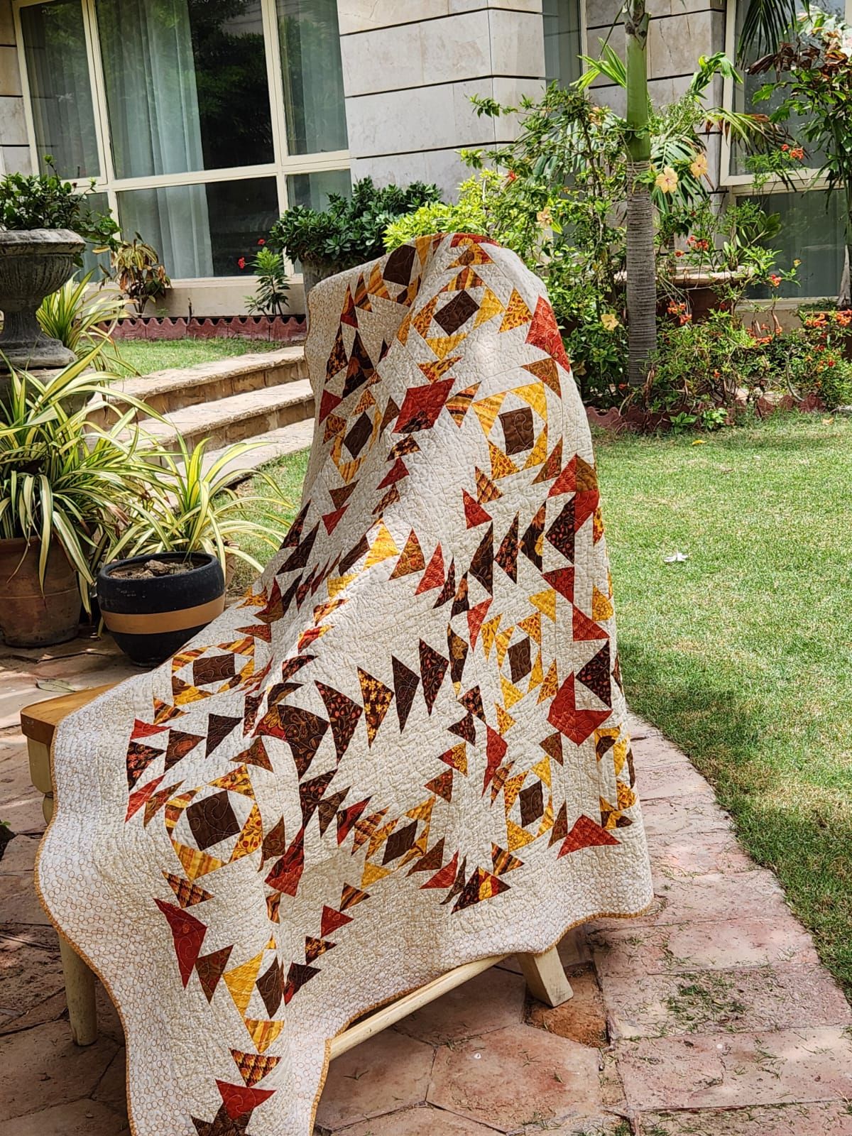 Autumn flying geese lap quilt draped over an outdoor chair