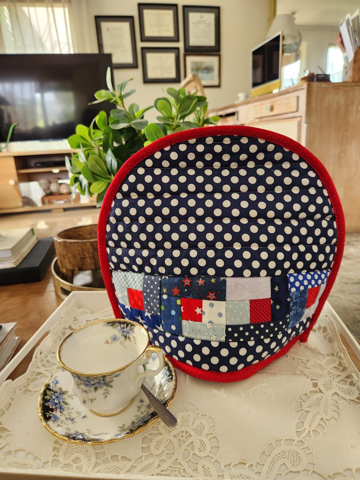 Navy polka dot tea cosy with a pieced band of red and blue scrap squares and red binding