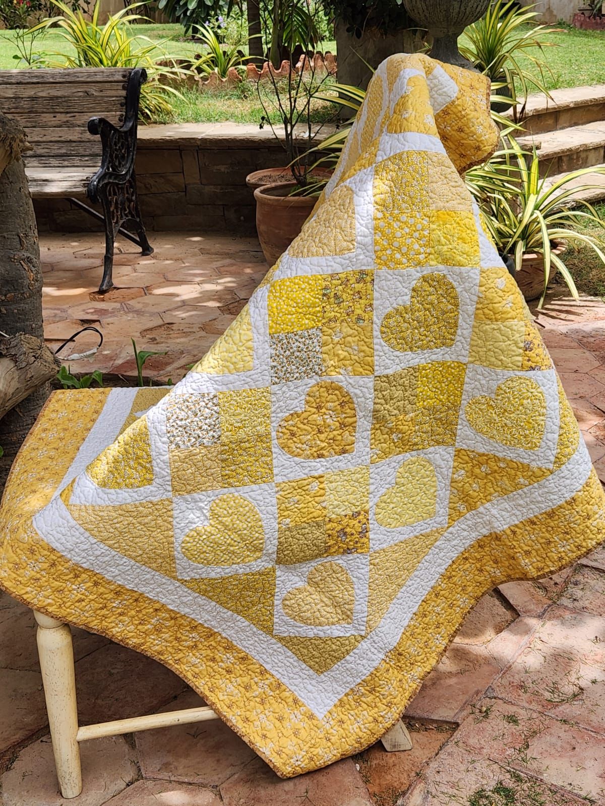 Golden hearts quilt draped over an outdoor chair in the garden