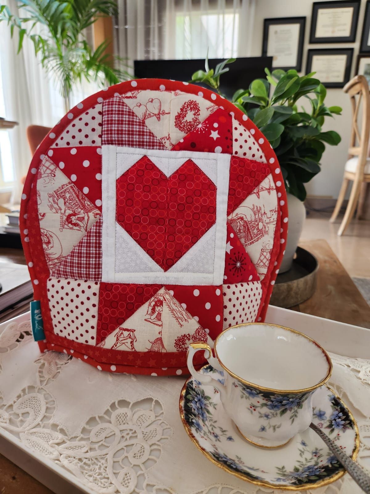 Front of a double-sided tea cosy: a red patchwork heart among red and white toile squares