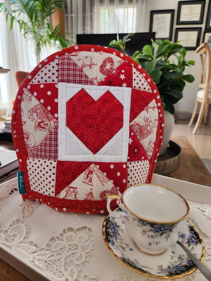 Front of a double-sided tea cosy: a red patchwork heart among red and white toile squares