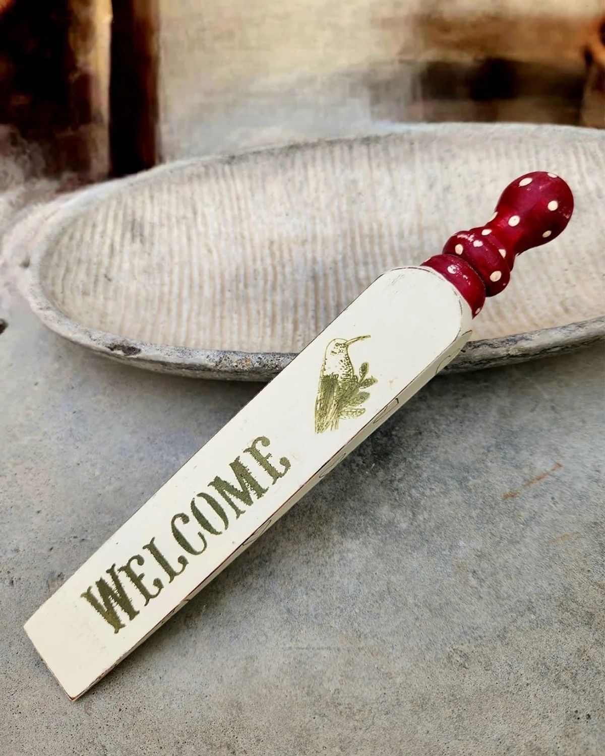 Painted wooden door wedge stencilled with WELCOME and a hummingbird