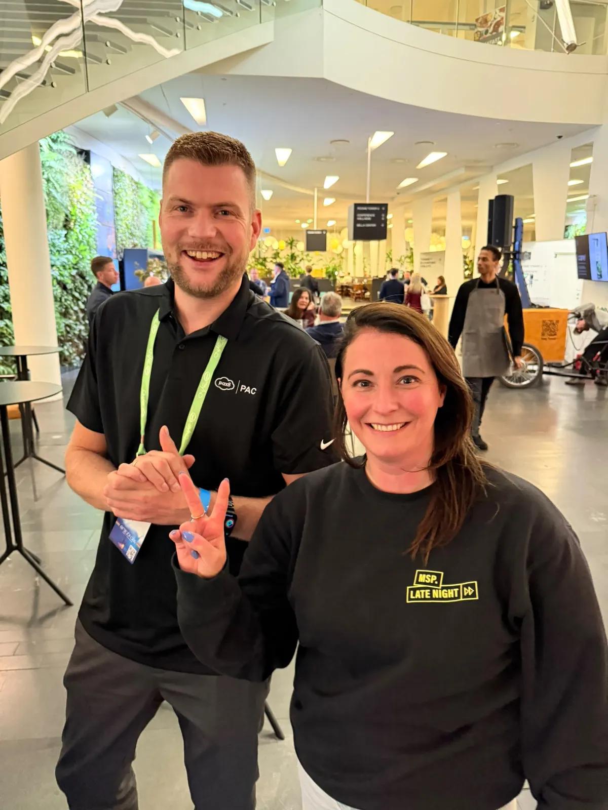 A man in a Pax8 shirt and a woman in an MSP Late Night sweater in the lobby of the event