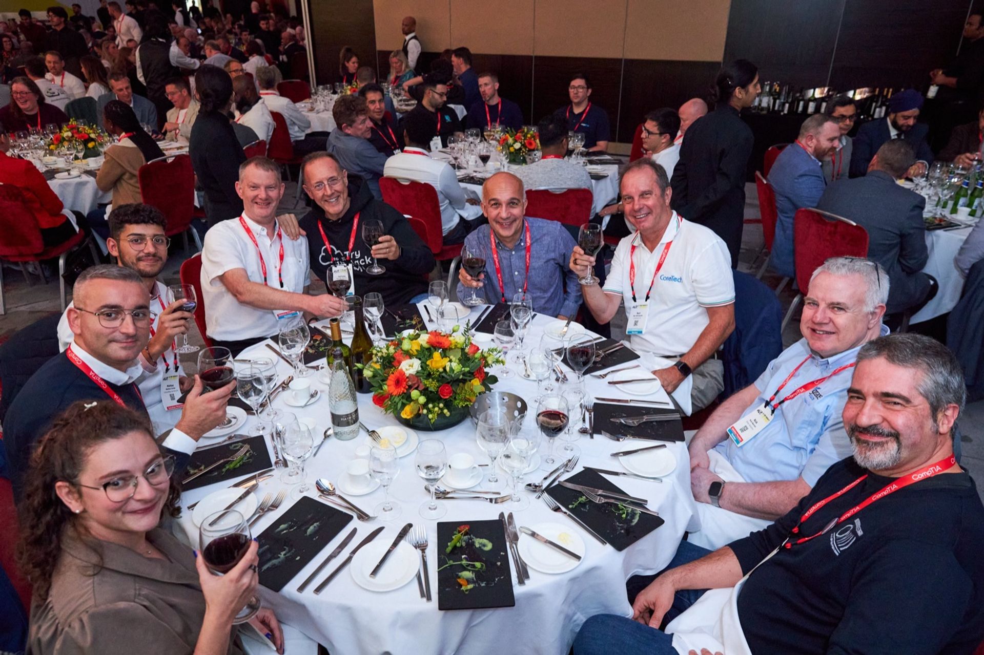Attendees of ChannelCon EMEA 2024 at a laid round table during dinner, raising their glasses to the camera
