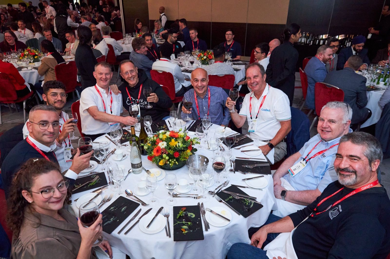 Attendees of ChannelCon EMEA 2024 at a laid round table during dinner, raising their glasses to the camera
