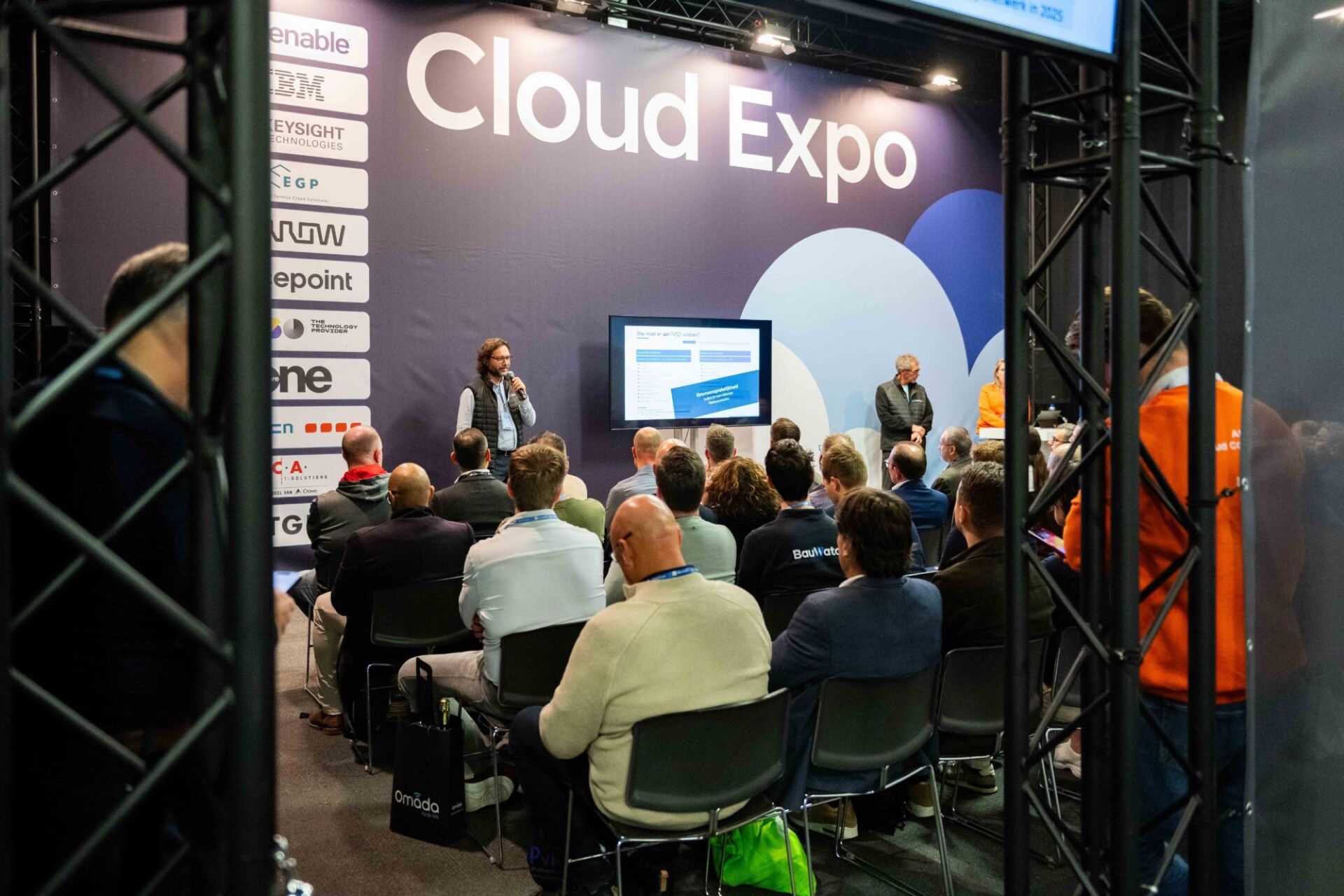 Publiek bij een sessie op Cloud Expo, voor de wand met het Cloud Expo-logo