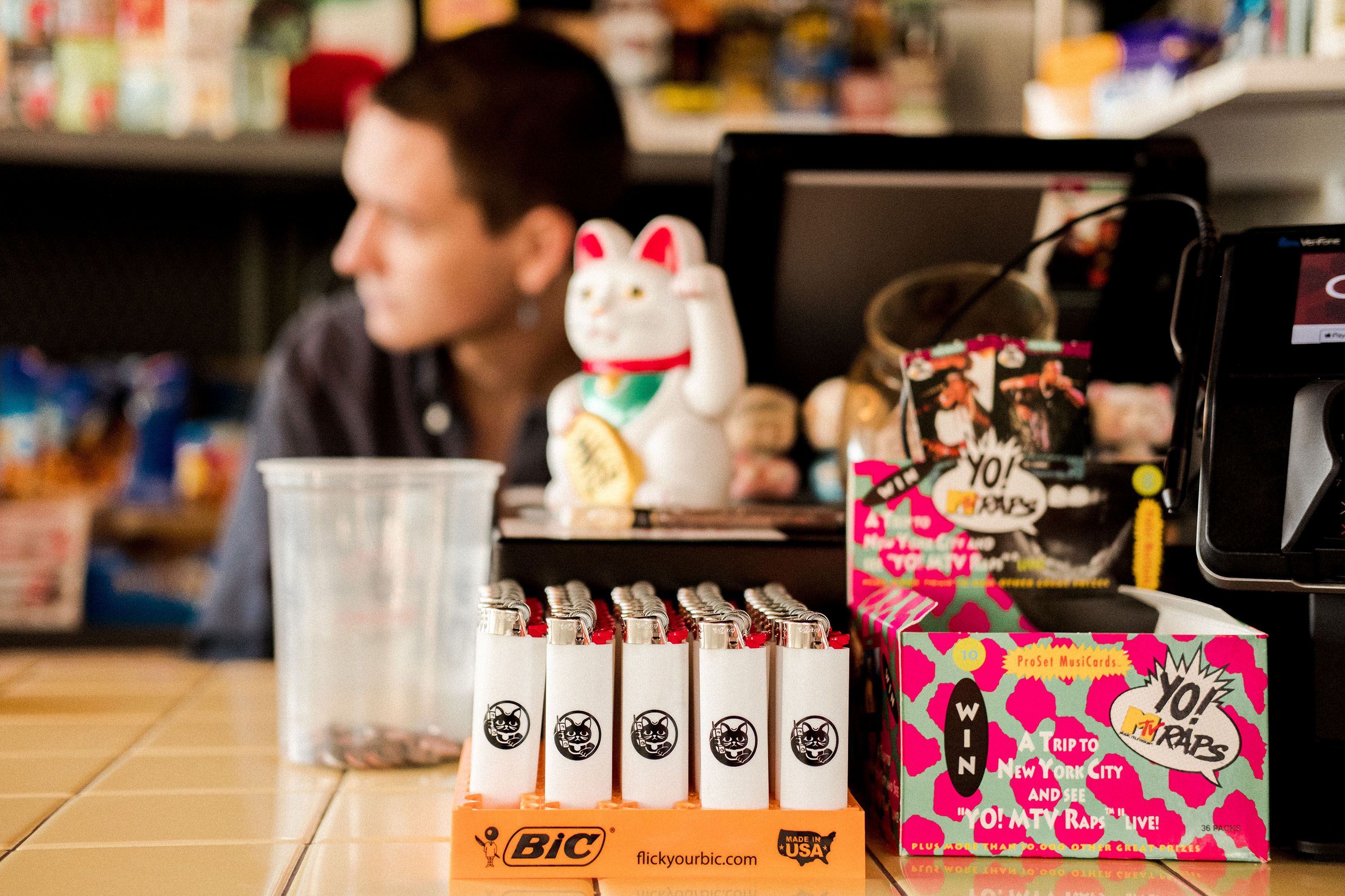 Retail counter at 1-800-Lucky with Lucky Cat decor, branded merchandise and colorful graphic packaging in the Wynwood food hall.
