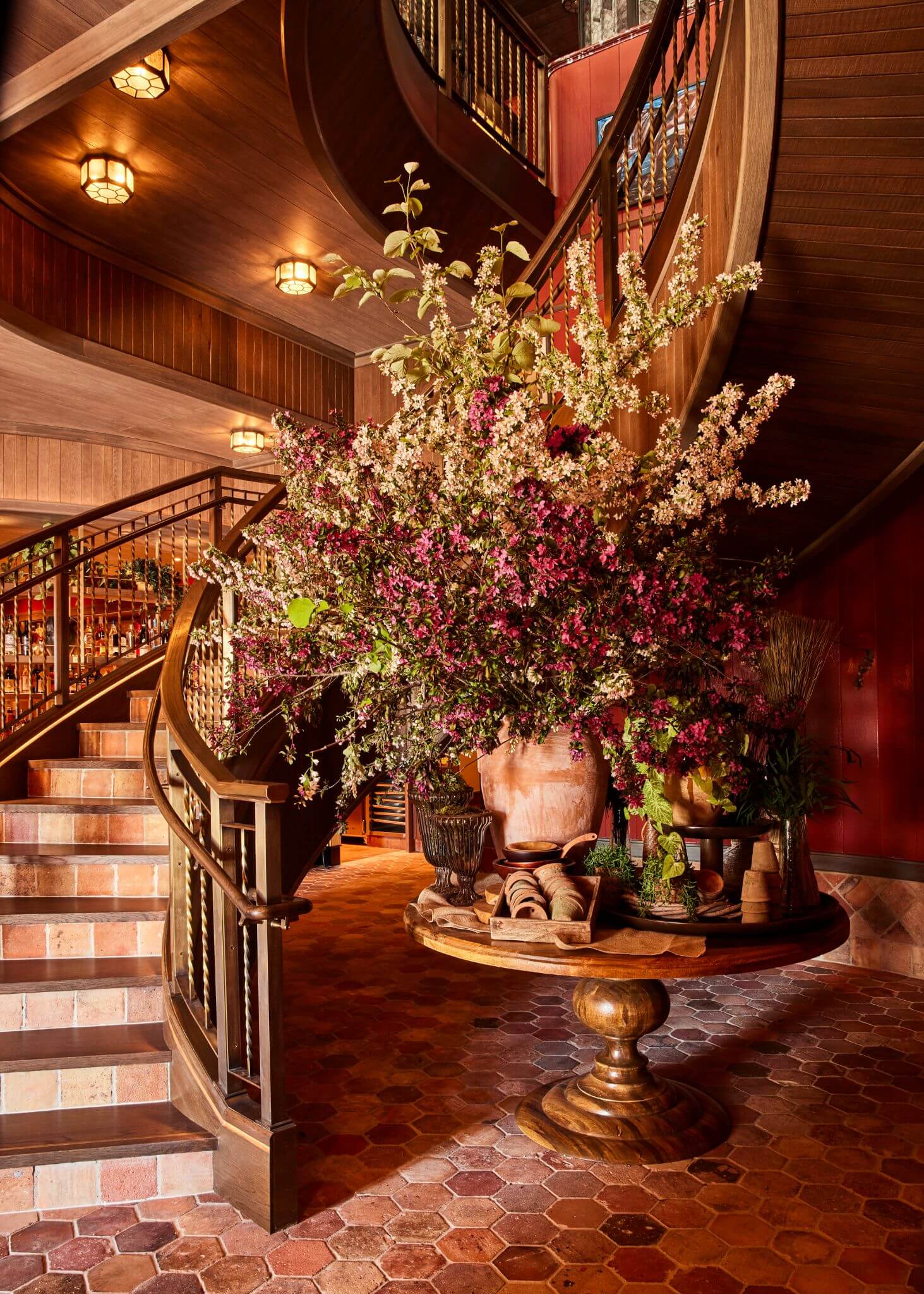 Carne Mare interior with dramatic floral arrangement, warm wood detailing and sweeping staircase at Pier 17 in New York.