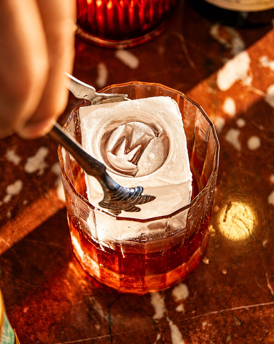 Carne Mare cocktail served over a monogrammed ice cube, reflecting the restaurant’s detailed food and beverage presentation.