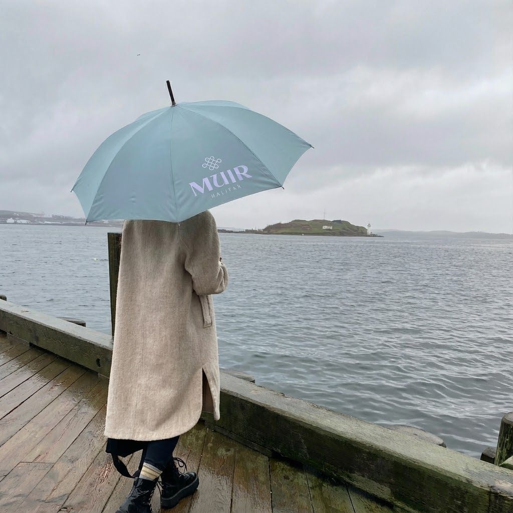 Branded umbrella overlooking Halifax Harbour at Muir Halifax. Love & War developed the hotel's brand strategy, naming, visual identity, and guest experience, extending the identity across custom amenities that connect guests to Nova Scotia's coastal landscape in every season.