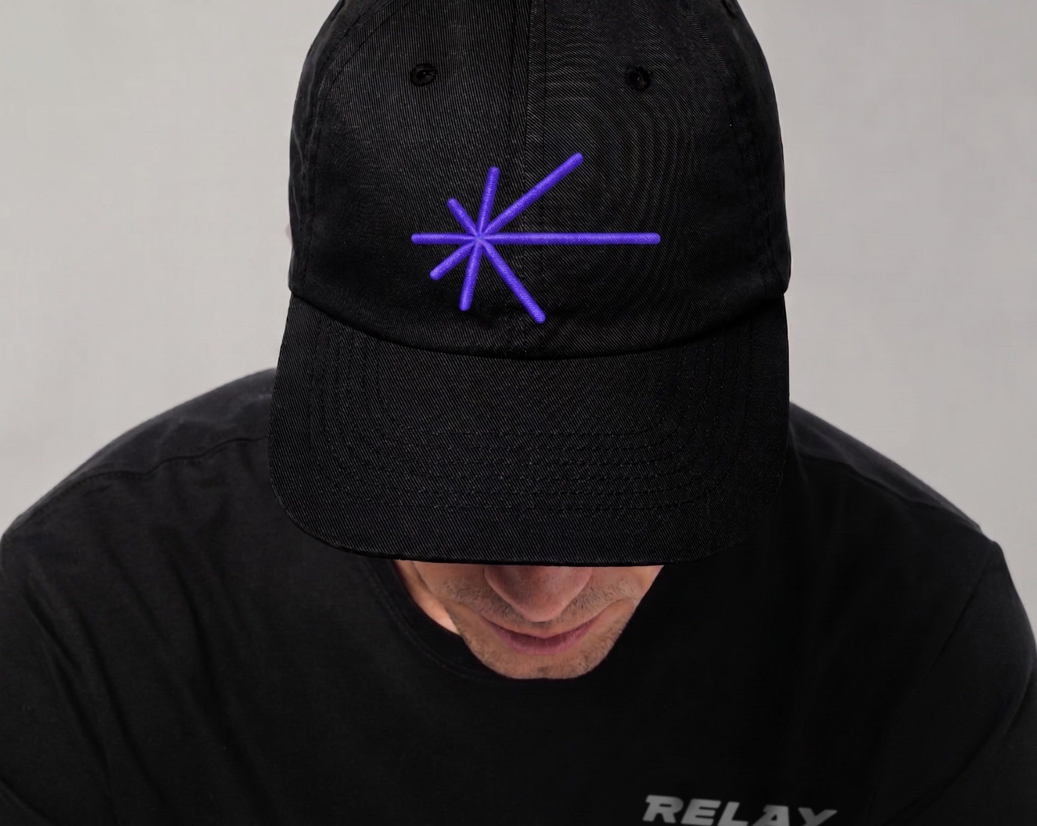 Black Relay cap featuring the purple starburst brand symbol, part of the crypto platform visual identity designed by Love & War.
