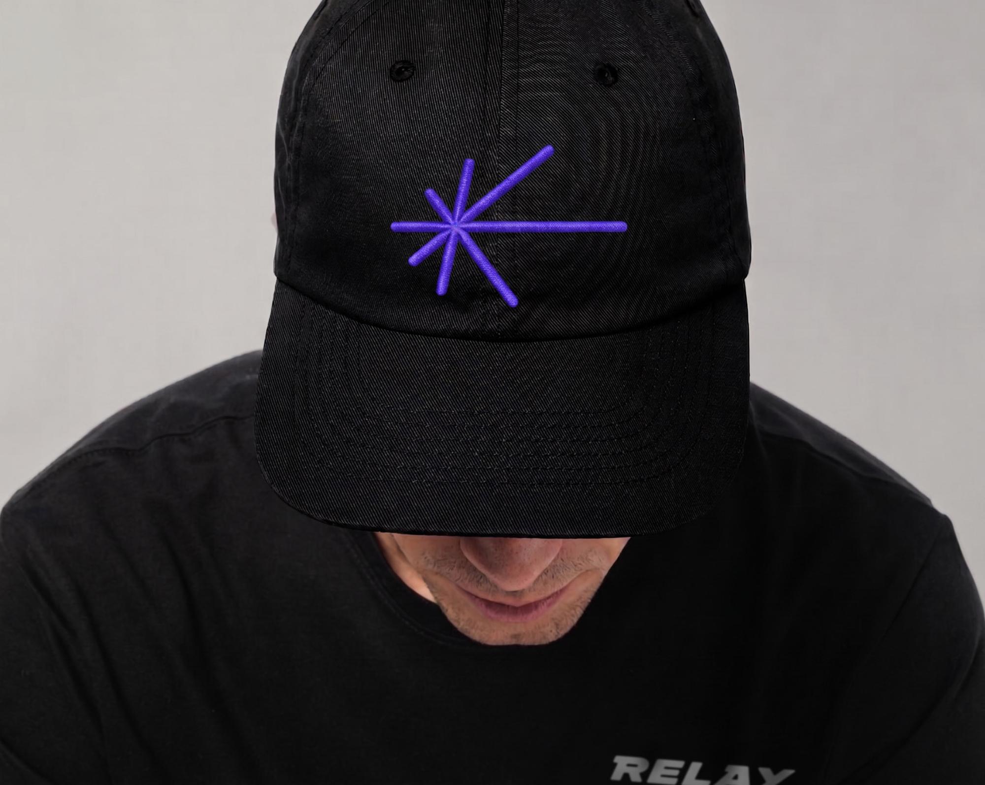 Black Relay cap featuring the purple starburst brand symbol, part of the crypto platform visual identity designed by Love & War.