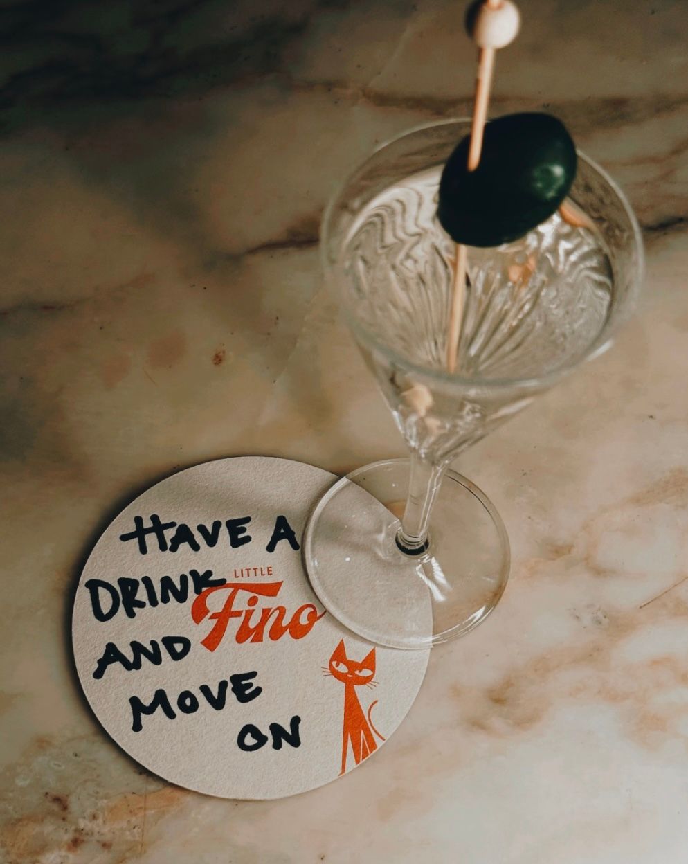 Custom illustrated cocktail coaster for Little Fino, the all-day Italian café and bar at The William Vale in Williamsburg, Brooklyn, featuring the playful line “Have a drink and move on,” the Little Fino logo and the brand’s black cat mascot. Love & War developed the name, brand concept, visual identity and custom illustrations for Little Fino, extending its personality across coasters, menus, packaging, signage, uniforms and other food and beverage touchpoints throughout the café and bar experience.