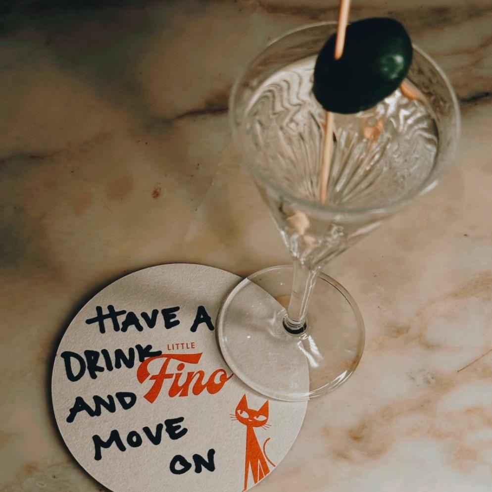 Custom illustrated cocktail coaster for Little Fino, the all-day Italian café and bar at The William Vale in Williamsburg, Brooklyn, featuring the playful line “Have a drink and move on,” the Little Fino logo and the brand’s black cat mascot. Love & War developed the name, brand concept, visual identity and custom illustrations for Little Fino, extending its personality across coasters, menus, packaging, signage, uniforms and other food and beverage touchpoints throughout the café and bar experience.