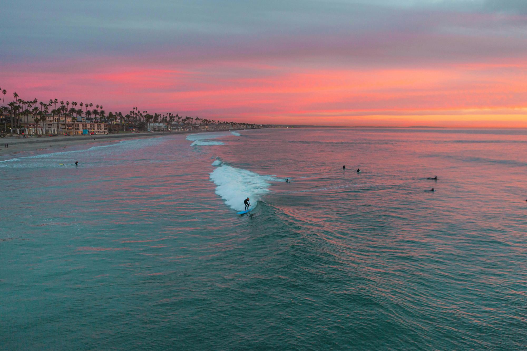 Surfers at sunset along the Oceanside, California coastline near Mission Pacific Beach Resort. Love & War drew on Oceanside’s surf culture, natural landscape, and creative community to develop the hotel’s concept, naming, visual identity, experience design, and marketing, creating a hospitality brand rooted in an authentic Southern California sense of place.