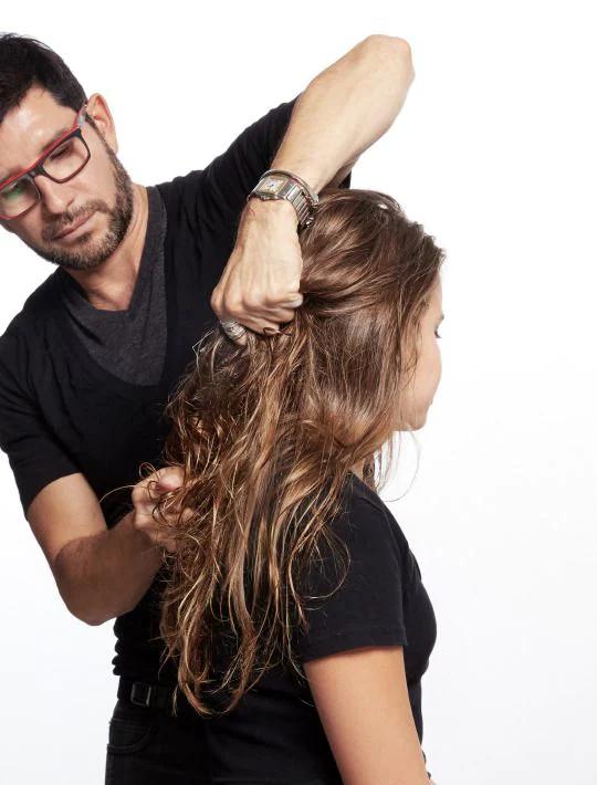 alt="Marco Peña working on a model's hair with a comb"