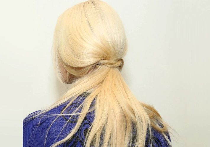 Image of the back of a blonde woman's hair in a thick ponytail